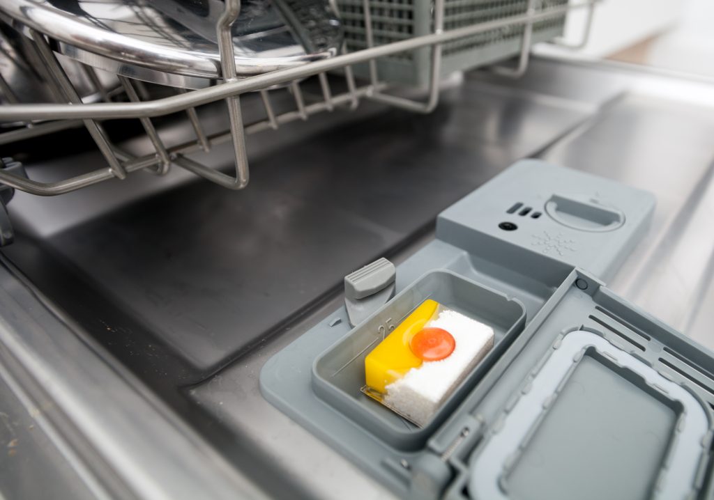 Detergent tablet in dishwasher machine close up